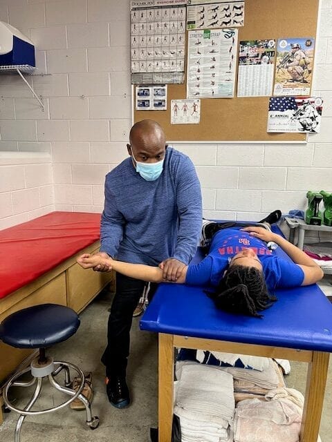 A woman receiving assisted stretch therapy from a male therapist in a comfortable setting.